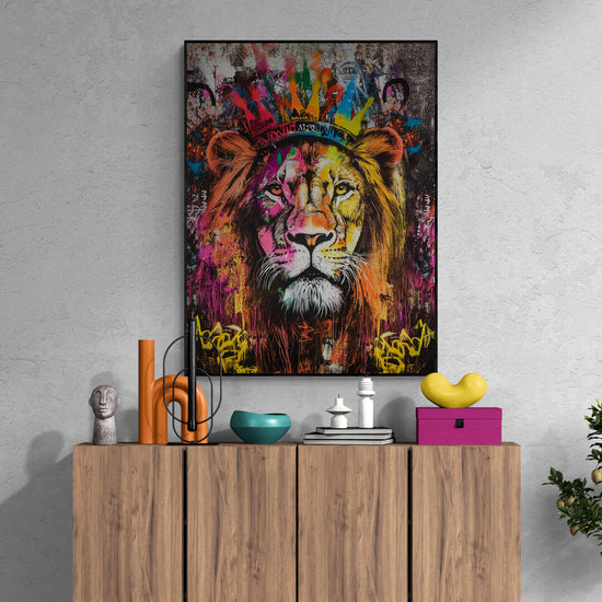  intérieur moderne avec un meuble en bois naturel orné de décorations comme des vases, des livres et des objets design et colorée. Au-dessus du meuble, un tableau accroché au mur représente un lion couronné dans un style vibrant de street art, avec des couleurs éclatantes de rose, jaune, vert et bleu. 