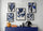 un mur décoré avec cinq cadres d'art abstrait de fleurs bleues, accompagné d'une table bleue avec des objets décoratifs tels qu'un vase, des livres et une lampe noire