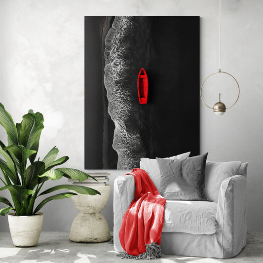 Le tableau représentant la barque rouge sur fond noir est accroché dans un salon au style tropical minimaliste, avec un fauteuil blanc, une couverture rouge assortie et une grande plante verte.