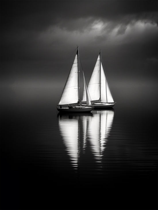 Photographie artistique de deux voiliers naviguant sur une eau calme, sous un ciel orageux. Le reflet lumineux des voiles contraste avec l’ambiance sombre, créant une atmosphère élégante et intemporelle. Idéal pour une décoration murale minimaliste et raffinée.