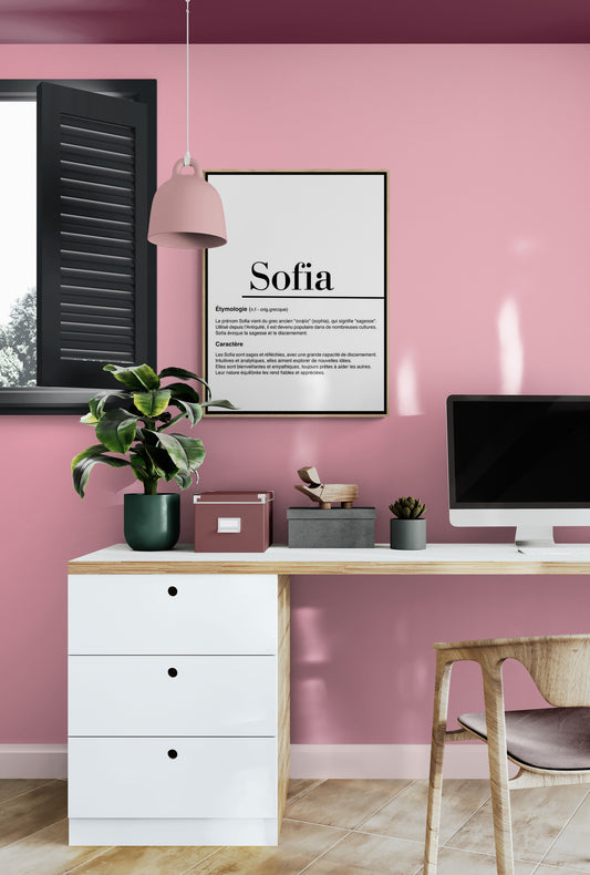Un tableau intitulé "Sofia" dans un bureau aux murs roses. Décoré avec un bureau en bois, une lampe rose, des plantes, et des accessoires organisés.