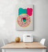 Grande déco mural dans une cuisine d'un donut dessiné à la main. Crème de couleur rose et est parsemée de pépites multicolores. L'arrière-plan du tableau est composé de deux traces de peinture, un beau rouge et l'autre verte, qui ajoutent de la profondeur et de la dimension à l'ensemble. Le tableau est très esthétique et aux couleurs vives. Minimaliste, ce tableau dégage une touche de fraîcheur et de féminité combinée au donut qui ajoute vie et gourmandise